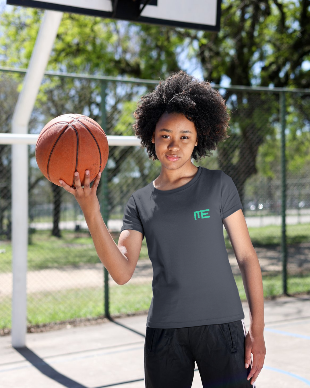 A girl with a basketball on her hand wearing a Momento Erolles t-shirt.