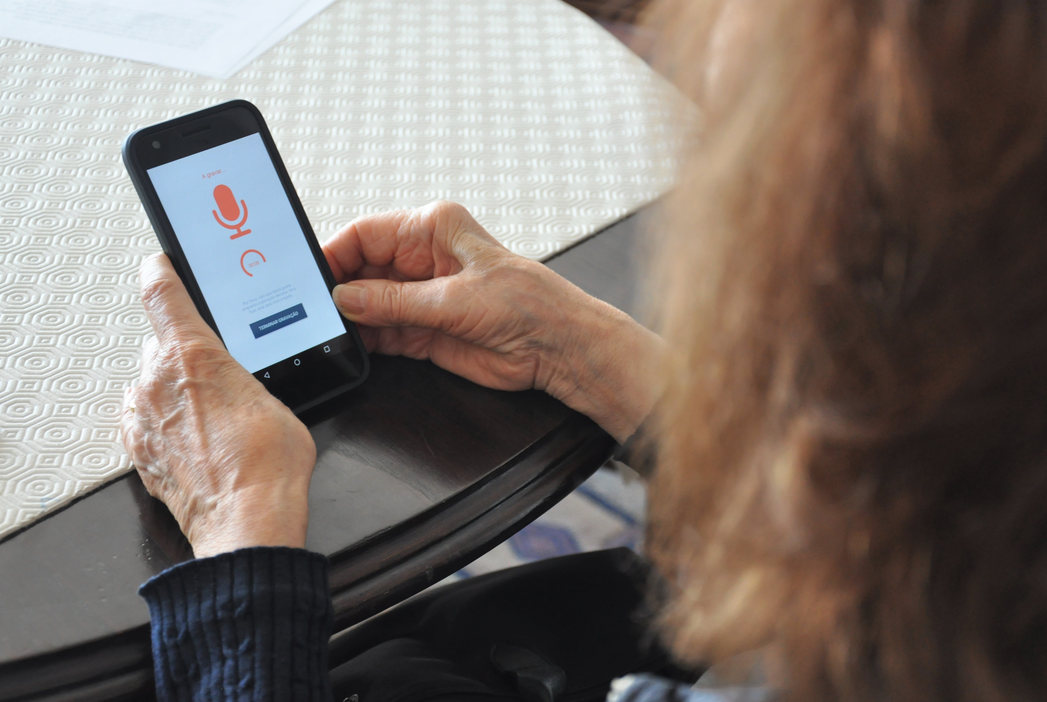 Elderly user handling a smartphone on which the interface of HealthTalks is visible.